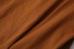 Gros plan d'un tissu en maille marron foncé montrant une texture douce de qualité