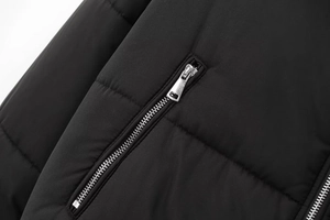 Detail view of smooth metal zipper and wide horizontal quilting on black padded jacket