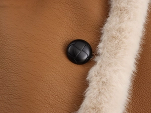 Détail du cuir grainé marron avec peau de mouton synthétique blanche et bouton tressé