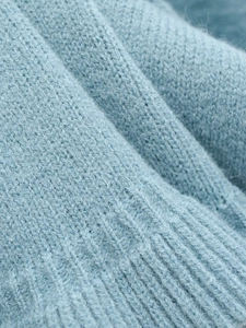 Close-up of light blue knit sweater fabric featuring soft texture and vertical ribbing