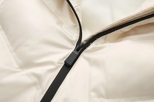 Détail de la fermeture éclair noire sur une veste matelassée crème au tissu de qualité
