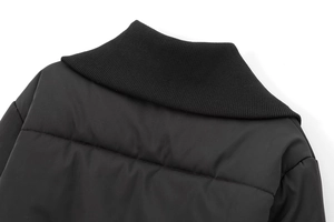 Detailed close-up of a black padded jacket showing ribbed knit collar and quilted fabric