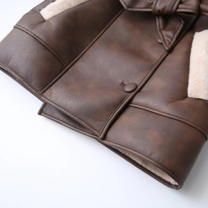 Detailed view of brown faux leather coat with white shearling trim and bow tie collar