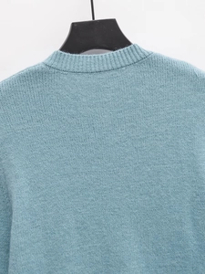 Detailed view of the light blue knit sweater rear neckline and fine stitched texture