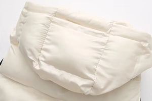 Détail du gilet matelassé beige à capuche montrant les coutures et la texture mate