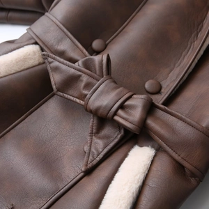 Detail of faux leather coat with contrast plush lining and belted bow tie waist