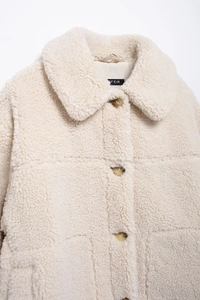 Detail of cream fleece jacket featuring textured faux fur, large collar, and brown buttons