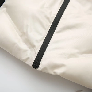 Détail de la fermeture éclair noire sur une veste matelassée blanc cassé mate et lisse