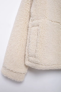 Detail shot of sherpa fleece jacket sleeve and large pocket in soft cream white color