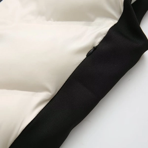 Détail de gilet matelassé blanc avec bordure côtelée noire et fermeture éclair invisible