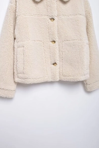 Close-up of beige teddy fleece jacket featuring lapel collar and amber buttons