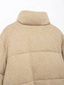 Detail of camel knit puffer jacket featuring a stand-up collar and quilted texture