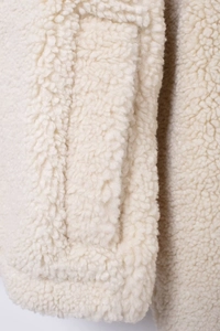 Close-up of premium cream sherpa fleece texture and stitching on a loose jacket