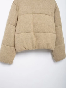 Detail of oatmeal knitted quilted jacket showing soft texture and wide puffer seams