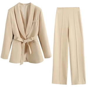 Detail of beige office suit set featuring belted blazer and pleated wide-leg trousers