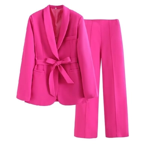 Detailed view of hot pink blazer lapel with matching waist belt and straight trousers