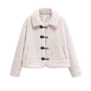 Detail of white faux shearling jacket featuring chic leather buckle straps and metal buttons