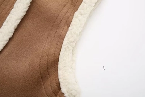 Detail showing high-quality flat stitching on brown suede and white lamb wool vest fabric