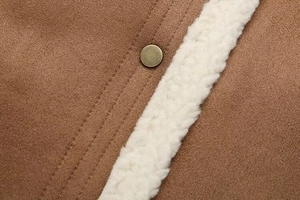 Close-up of brown faux suede vest with plush white shearling trim and metal snap button