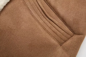 Close-up of decorative stitching on brown faux suede vest with soft sherpa lining