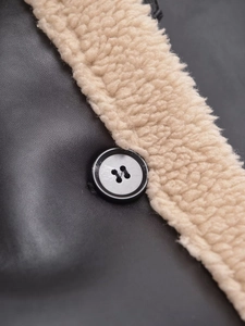 Gros plan d'une veste en similicuir noir avec bordure en peau lainée et bouton rond