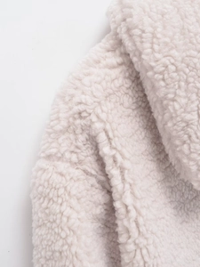 Close-up macro texture of soft cream-white faux shearling fabric for winter jacket