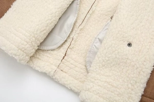 Detailed close-up of brown suede fabric with warm sherpa fleece lining and metal snap button