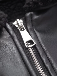 Gros plan sur la fermeture éclair argentée et la texture du similicuir noir du blouson