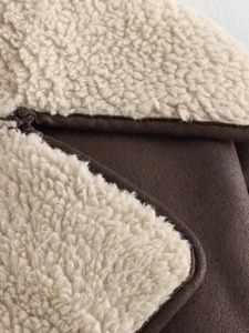 Close-up of brown suede fabric with cream faux shearling lining on a winter jacket