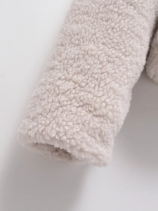 Close-up of soft beige faux shearling fabric showing thick fleece texture on the cuff
