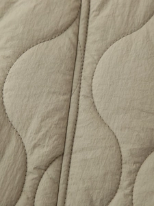 Détail macro du tissu matelassé ondulé sur une veste bouffante couleur kaki