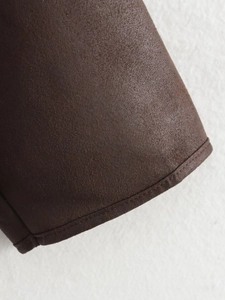 Close-up of deep brown suede fabric detail with neat stitching on a winter jacket