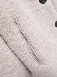 Detailed macro view of cream fleece jacket pocket with satin lining and black button detail