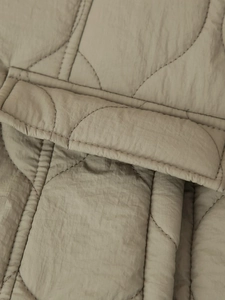 Détail de la veste matelassée kaki avec surpiqûres vagues et texture du rabat de poche