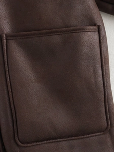 Detail of dark brown faux shearling jacket showing high-quality stitching on square pocket