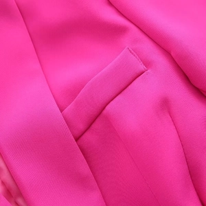 Detail of hot pink blazer fabric showing fine stitching and high-quality pocket texture