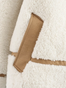 Detailed view of white faux shearling texture with brown suede pocket trim and stitching