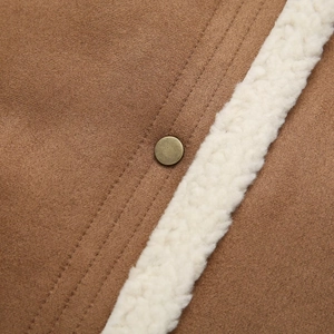 Macro detail of brown faux suede vest featuring bronze button and white shearling trim