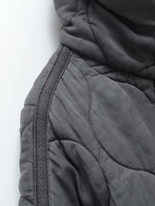 Détail d'une veste matelassée gris foncé avec col montant et texture en tissu sergé premium