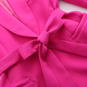 Detail of rose pink blazer showing waist bow tie, lapel structure, and pocket stitching