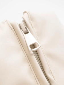 Close-up of matte ivory zipper on soft PU leather texture for cropped winter jacket