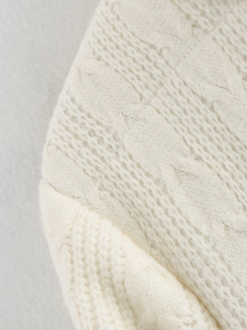 Detailed close-up of cable knit pattern on a cream-colored cardigan with premium texture