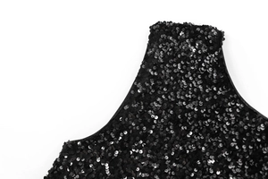 Close-up of black sequin fabric texture with detailed edge stitching on party dress