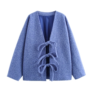 Dettaglio della giacca bouclé celeste con eleganti lacci a fiocco e scollo a V sottile