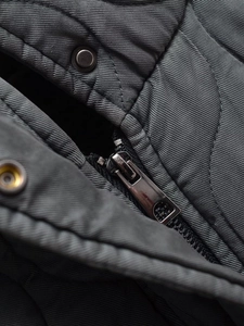 Détail de la veste matelassée gris foncé avec fermeture éclair et bouton métal