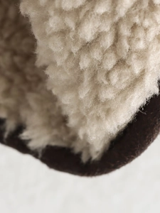 Detailed close-up of thick beige faux shearling lining and brown suede outer fabric