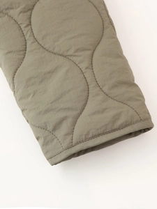 Détail de la doudoune matelassée vert armée avec coutures ondulées et bordure de finition