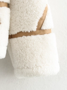 Macro detail of faux shearling jacket showing fleece texture and brown suede trim