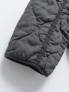 Vue macro détaillée du tissu matelassé gris foncé et de la couture soignée sur le poignet