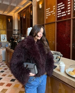 Dettaglio giacca in ecopelliccia bordeaux e borsa di lusso con strass per donna